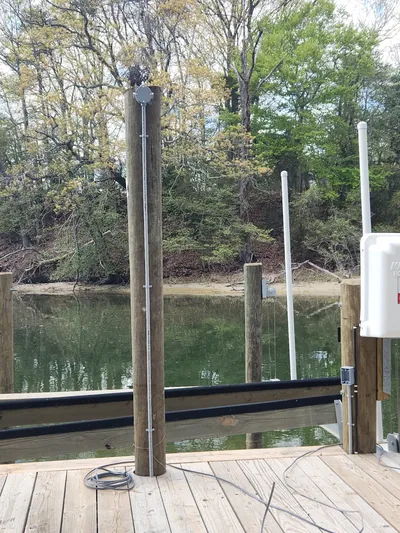 A power pedestal on a wooden dock beside a piling, with a tidal creek and trees behind