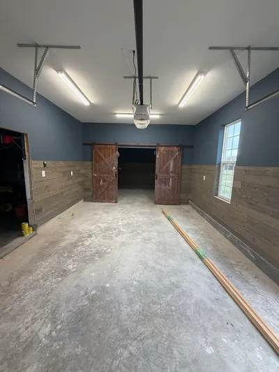 The same garage looking the other way, to a pair of sliding wood barn doors under strip lights