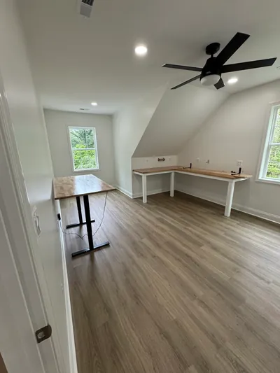 A loft room with a built-in butcher block desk under the roof slope, a ceiling fan and recessed lights